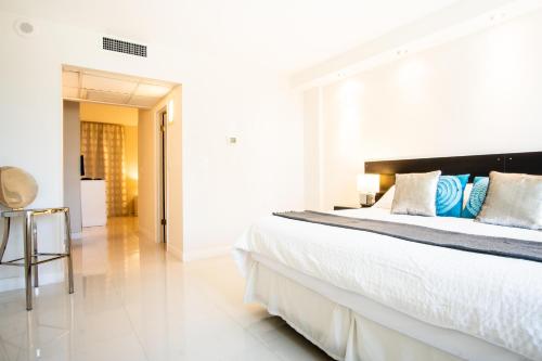 a white bedroom with a large bed with blue pillows at Ocean Reserve 927 in Miami Beach