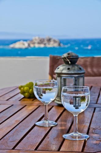 two wine glasses sitting on top of a wooden table at Ydreos Studios & Apartments in Mikri Vigla