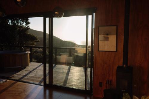an open glass door to a deck with a view at Foudre Suite with Hot Tub at Barrelled Wines Raglan in Raglan