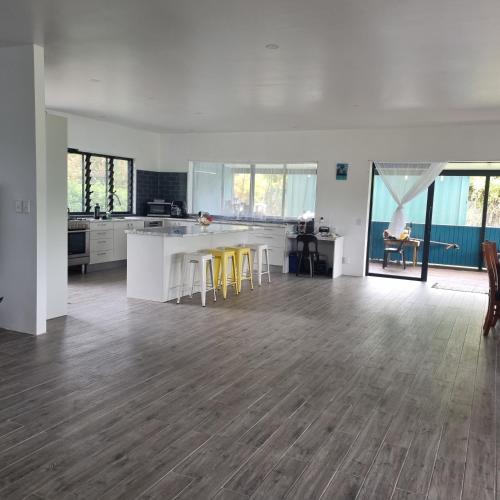 a kitchen with white counters and yellow stools at Mama MIREKA Homestay in Arorangi