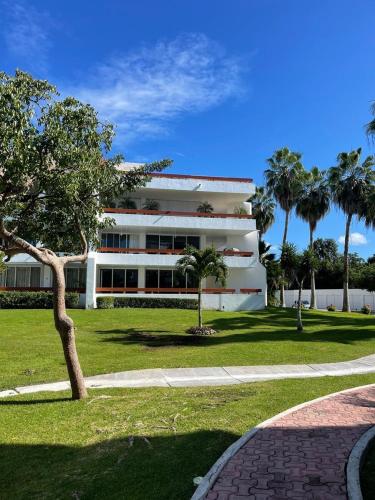 a white building with palm trees in front of it at Residencias Reef in Cozumel