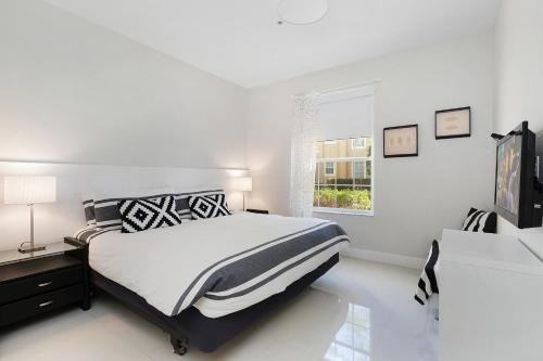 a white bedroom with a bed and a window at One in a Minion #102 in Orlando