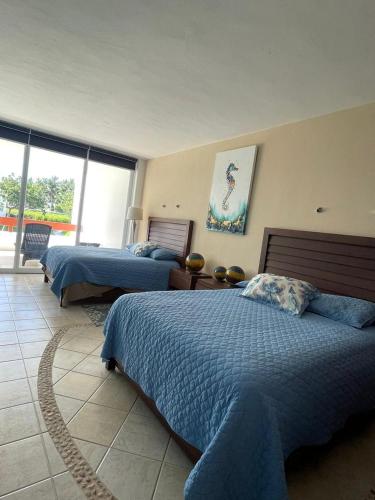 a bedroom with two beds and a balcony at Residencias Reef in Cozumel