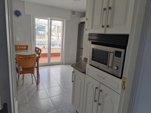 eine Küche mit einer Mikrowelle und einem Tisch mit Stühlen in der Unterkunft Ático espacioso en zona céntrica in Sarria