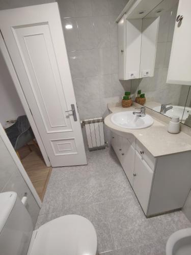 a white bathroom with a toilet and a sink at Ático espacioso en zona céntrica in Sarria