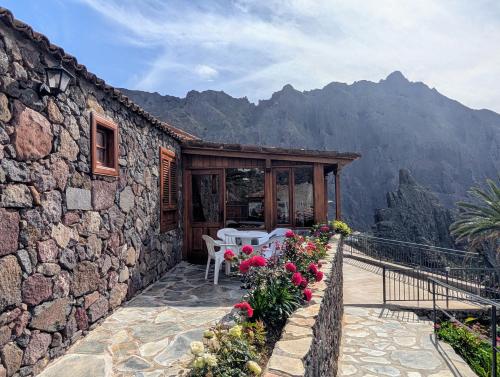 a stone house with a patio with tables and flowers at Masca - Casa Rural Morrocatana - Tenerife ONLY ADULTS in Masca