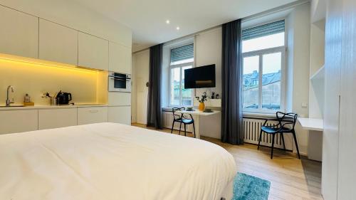 a bedroom with a large white bed and a kitchen at Studio Fischer à la Pétrusse 301 in Luxembourg