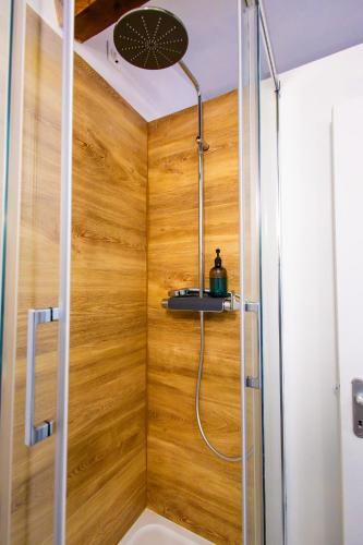 une douche dans une salle de bain avec un mur en bois dans l'établissement Appartement Jelyad Terres Fortes 3 à 10 minutes de Disney, à Chanteloup-en-Brie
