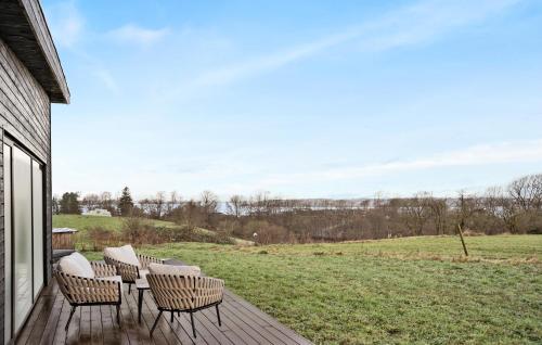 a deck with chairs and a table and a field at 3 Bedroom Stunning Home In Løgstrup in Løgstrup