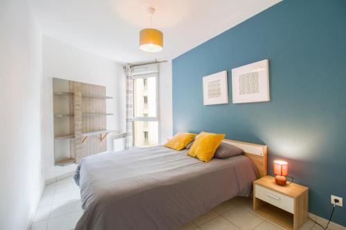 - une chambre bleue avec un lit et des oreillers jaunes dans l'établissement Palestro -St charles- Vieux Port, à Marseille