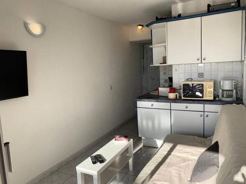 małą kuchnię z białymi szafkami i kuchenką mikrofalową w obiekcie Résidence Port Nature Colline 3 - Appartement T2 4 pers - Port Nature Colline 3 MAE-2874 w Cap d'Agde