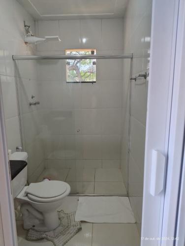 a white bathroom with a toilet and a shower at Kitnetes Mobiliadas in Estancia do Castello