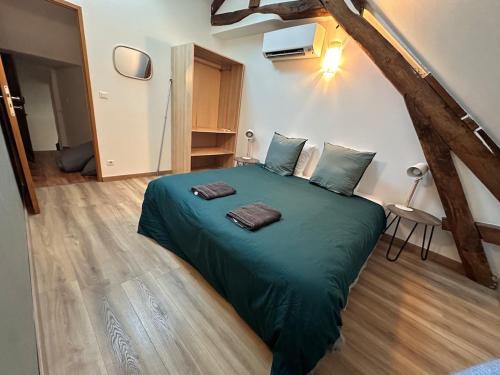 a bedroom with a green bed with two towels on it at La Ruche in La ForestiÃ¨re