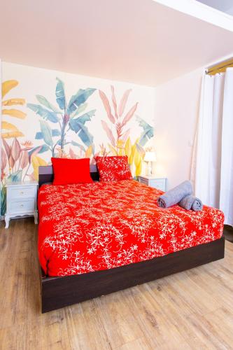 une chambre avec un lit rouge avec des oreillers rouges dans l'établissement Appartement Jelyad Terres Fortes 2 à 10 minutes de Disney, à Chanteloup-en-Brie