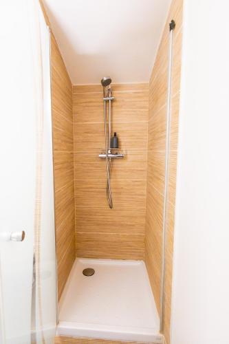La salle de bains est pourvue d'une douche et de murs en bois. dans l'établissement Appartement Jelyad Terres Fortes 2 à 10 minutes de Disney, à Chanteloup-en-Brie