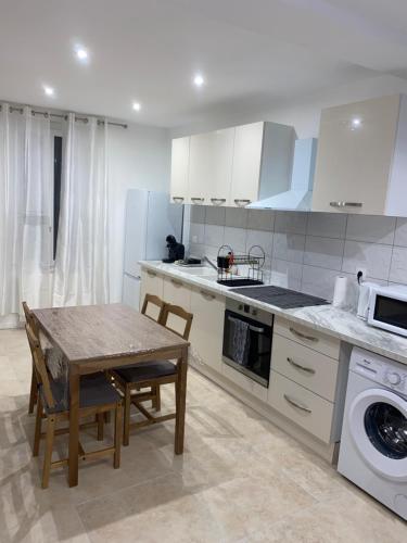 une cuisine avec des armoires blanches et une table avec des chaises dans l'établissement Joli maison refait à neuf #2, à Vierzon