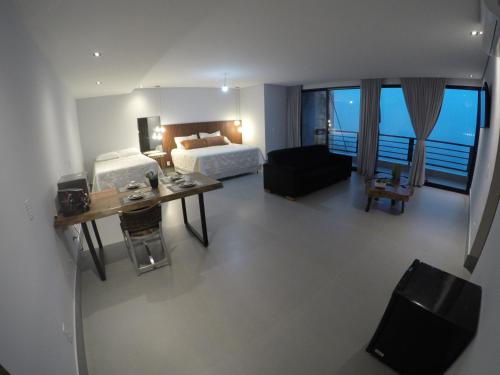 Un dormitorio con una cama y un escritorio en una habitación. en Lounge Suites De Luxo Piuva, en Ilhabela