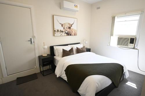 a bedroom with a bed with a cow picture on the wall at Townhouse in Glen Iris in Glen Iris