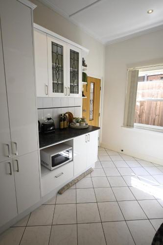 a kitchen with white cabinets and a tile floor at Townhouse in Glen Iris in Glen Iris