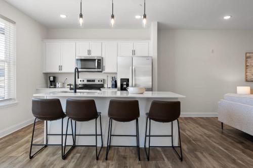 a kitchen with a counter and four bar stools at Chic 2BR at The Poplin - Southside Chattanooga in Chattanooga