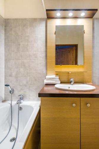 une salle de bain avec une baignoire et un lavabo et une baignoire dans l'établissement Lagrange Vacances Cybèle, à Brides-les-Bains