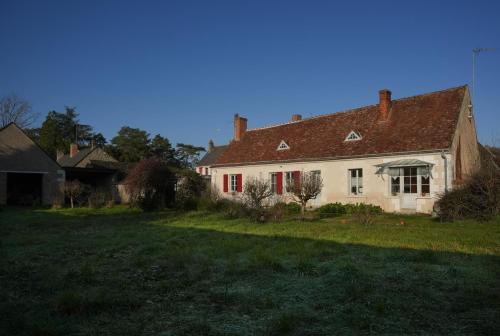 an old white house with red windows and a yard at Le gîte de la Roche in Chenonceaux