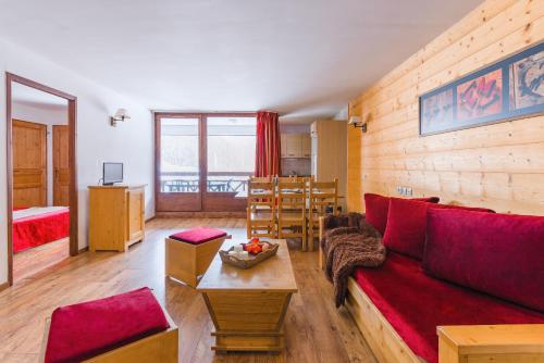 een woonkamer met een rode bank en een tafel bij Lagrange Vacances Cybèle in Brides-les-Bains