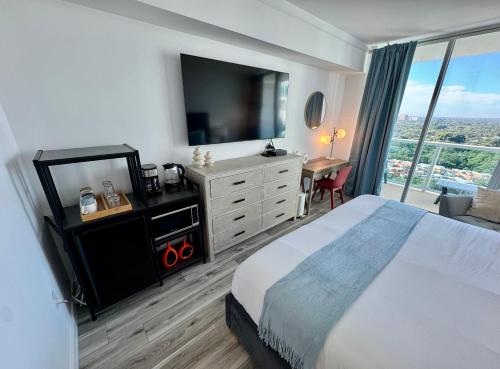 a bedroom with a bed and a dresser with a television at Balcony Ocean View ! Pool - WiFi - Gym - Parking in Miami
