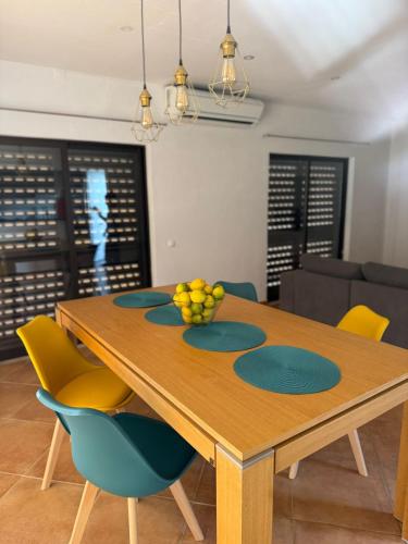 a dining room table with yellow and blue chairs at Dave Place - 3 Bedroom House in Alte