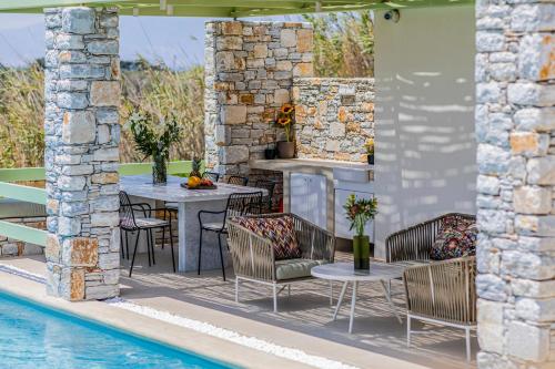 a patio with a table and chairs next to a pool at Plioni Villas With Private Pool & Suites With Hot Tub in Mikri Vigla