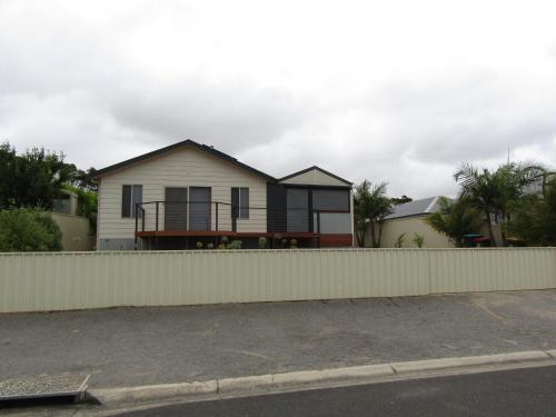 a white house with a fence in front of it at The Shack at Vincent in Port Vincent