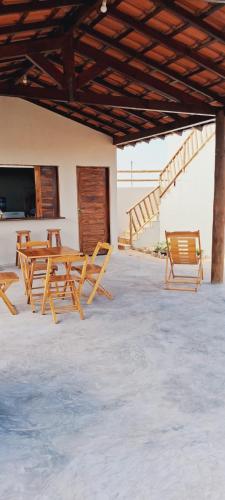 a group of wooden tables and chairs under a roof at Chalé sol de Macapá 1- Sua Casa pertinho do Mar in Luis Correia