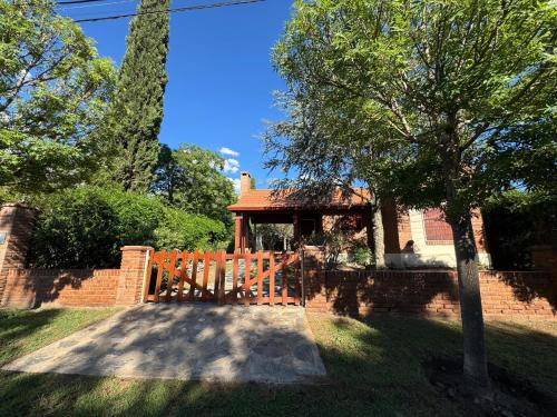 a brick house with a wooden gate in a yard at Merlinda in Merlo