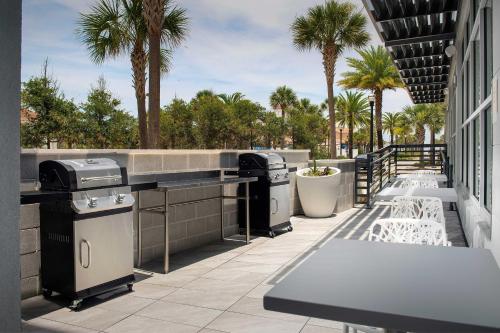 a patio with a grill and tables and palm trees at Element Jacksonville Beach in Jacksonville Beach