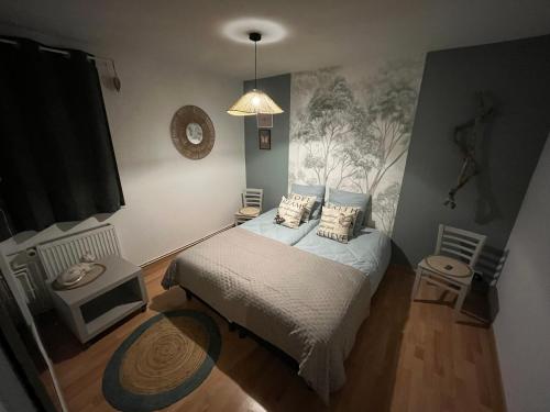 une chambre avec un lit et un tableau au mur dans l'établissement Comme à la maison, à Saint-Aubin