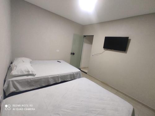 a small room with a bed and a flat screen tv at Balihahls in Prudentópolis