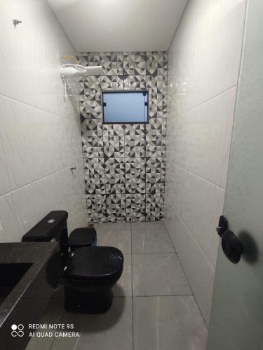 a bathroom with a toilet and a tv on a wall at Balihahls in Prudentópolis
