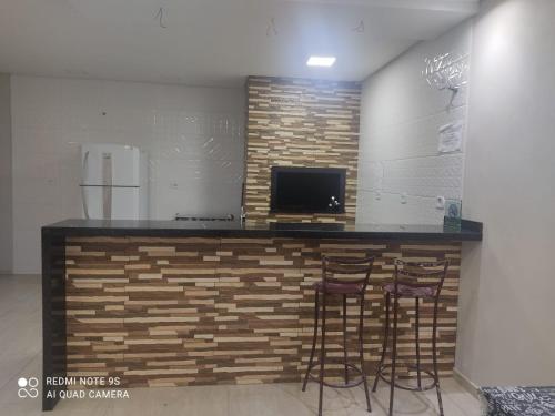 a kitchen with a counter with three bar stools at Balihahls in Prudentópolis