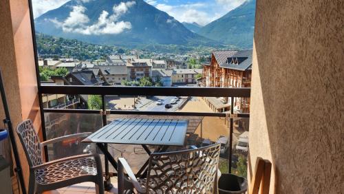 une table sur un balcon avec vue sur une ville dans l'établissement L'Escapade du Prorel, à Briançon