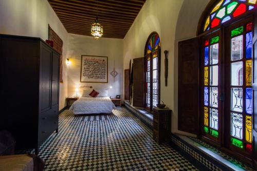 a bedroom with a bed and stained glass windows at Dar Nejma in Fez