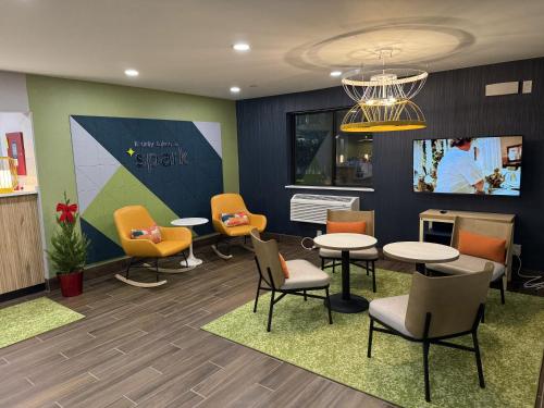 a waiting room with tables and chairs and a tv at Spark by Hilton Norfolk in Norfolk