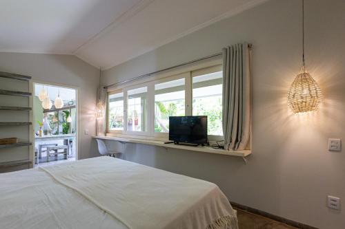 a bedroom with a bed and a window with a television at Casa Kokoro in Pipa