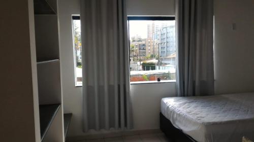 ein Schlafzimmer mit einem Bett und einem Fenster in der Unterkunft Casa de praia Enseada in Guarujá