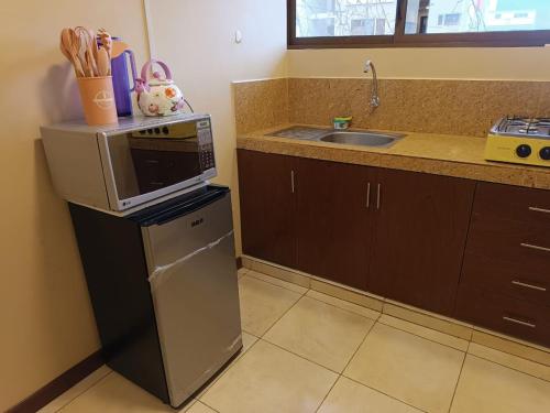 una cocina con un microondas encima de un refrigerador en Departamento Bonito 2, en Loja