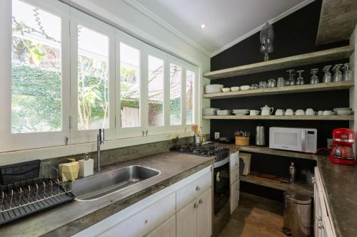 a kitchen with a sink and a counter with windows at Casa Kokoro in Pipa