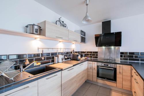 une cuisine avec des armoires en bois et des appareils en acier inoxydable dans l'établissement Appartement tout équipé proche Paris - Stade de France, à Épinay-sur-Seine