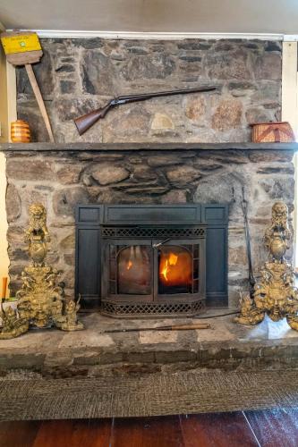 a stone fireplace with a fire burning in it at Gray Ghost Inn in West Dover