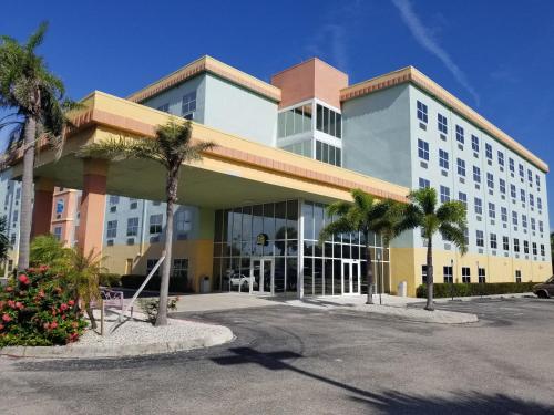 a building with palm trees in a parking lot at Allure Suites of Fort Myers in Fort Myers
