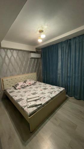 a bed in a bedroom with a blue curtain at Three Star in Almaty
