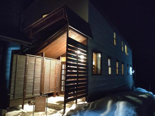 a building with a staircase in the snow at night at Hakuba Norikura Wakaguri Guesthouse in Otari